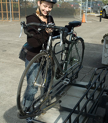 Photo of bicyclist placing bike on bus rack